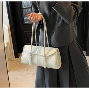 Detail of off-white baguette bag with glossy leather texture and double silver buckles