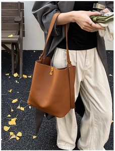Gros plan détaillé du sac seau en cuir marron avec fermoir pivotant en métal doré