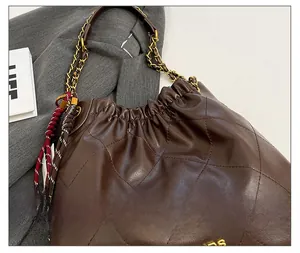 Detailed view of brown quilted leather tote bag with gold chain strap and stitching
