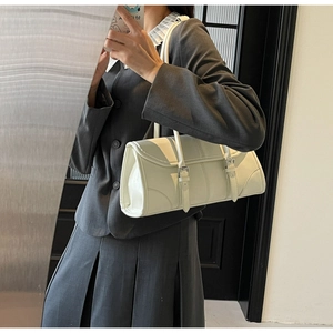 Detail of white baguette bag with silver buckles and fine stitching on faux leather surface