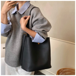 Détail du sac seau noir en cuir avec boucles dorées et bandoulière réglable