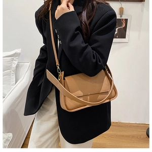Detail of brown litchi pattern leather shoulder bag with gold metal buckle on a model