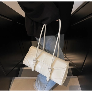 Detail view of a white patent leather baguette bag featuring stylish double buckle straps