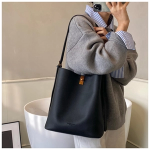 Détail du sac seau noir en cuir grainé avec fermoir doré et lettrage en relief élégant