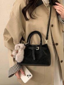 Minimalist black suede bucket bag with contrast stitching and plush bunny pendant