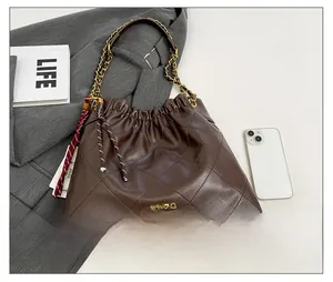 Detail of brown quilted leather shoulder bag with gold chain strap and striped silk scarf