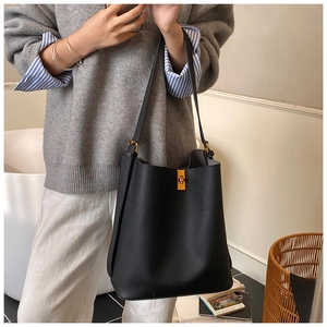 Détail du sac seau en cuir grainé noir avec fermoir rotatif doré et bandoulière