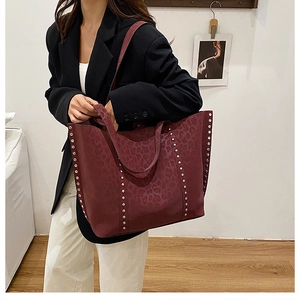 Detail of burgundy leopard print tote bag with silver studs on the shoulder straps