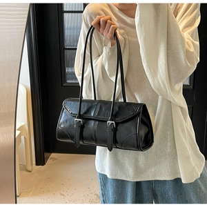 Detail of vintage black oil wax leather baguette bag with dual metal buckle straps