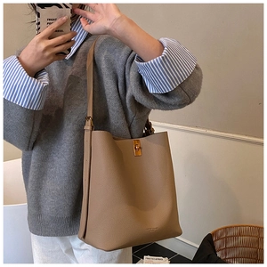 Détail du sac seau kaki montrant la texture grainée et le fermoir rotatif doré élégant