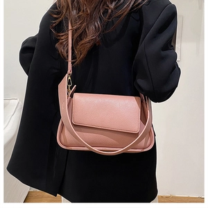 Detail of rose pink lychee leather handbag with golden hardware on a black blazer