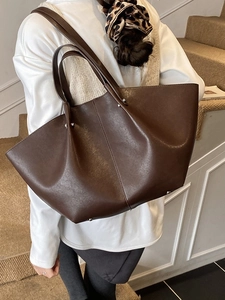 Large brown wing-shaped tote bag in textured faux leather with metallic rivets