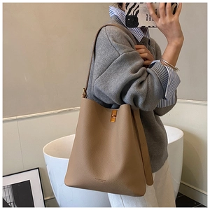 Détail du sac seau en cuir camel montrant la bandoulière réglable et le fermoir doré