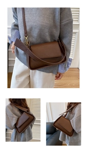Detail of dark brown lychee texture leather shoulder bag with wide strap and gold buckle