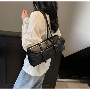 Detail of black wax leather baguette bag with silver buckles on white top outfit