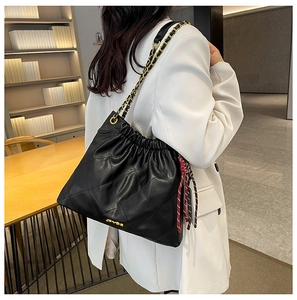 Detail of black quilted bucket bag featuring drawstring closure and gold chain strap