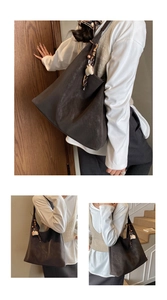 Detail view of large dark brown suede tote bag featuring side charm and soft retro texture