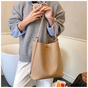 Détail du sac seau beige en cuir avec lettrage doré FASHION & BAGS sur le devant