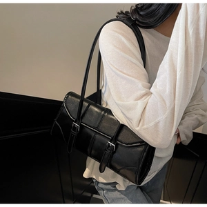 Side view of a black oil-wax leather underarm bag with double straps and buckle detail