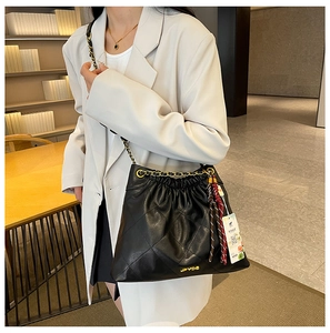 Close-up of black quilted bucket bag with gold chain strap and elegant silk scarf detail