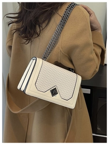 Detail of cream white chain bag with woven texture and diamond metal buckle on camel coat