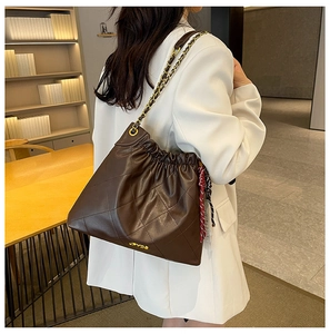 Detail of dark brown quilted leather tote bag with gold chain strap and drawstring closure