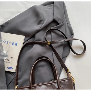 Detail of dark brown leather bucket bag with gold hardware and removable shoulder strap