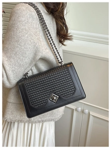 Detail of black woven shoulder bag with silver clasp and metallic chain strap