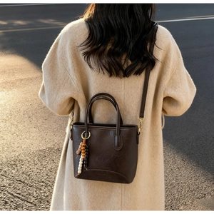 Close-up of vintage brown leather bucket bag with beaded tassel and gold hardware
