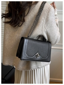 Detail of black matte leather underarm bag with woven texture and diamond metal buckle