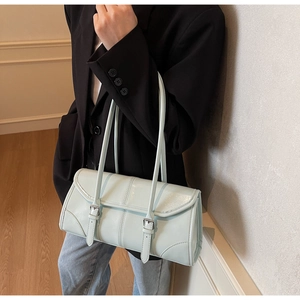Close-up of mint green oil wax leather baguette bag with silver buckles on model