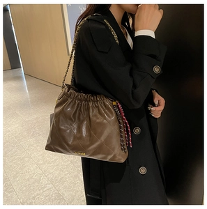 Detail of dark brown quilted tote bag with drawstring closure and golden chain strap