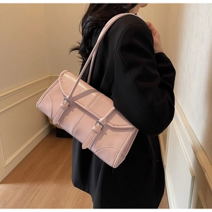 Side view of a light pink baguette bag worn by a model in a black blazer suit