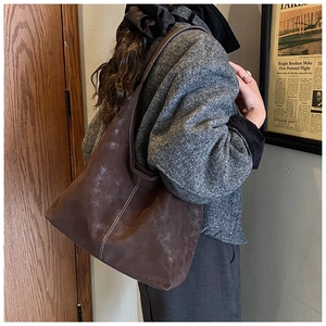 Detail of dark brown tote bag featuring fine white stitching and vintage matte leather texture