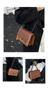 Detail of brown woven leather bag featuring a diamond metal lock and grey chain strap