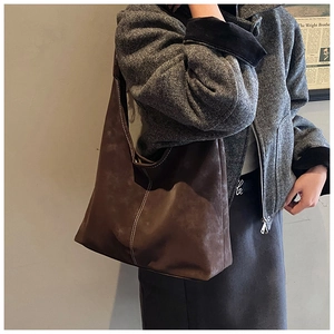 Detail of large brown hobo tote bag featuring contrast white stitching and matte texture