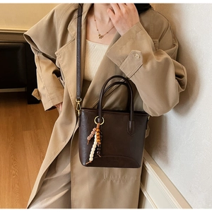 Detail of dark brown leather bucket bag with retro bead charm and detachable strap