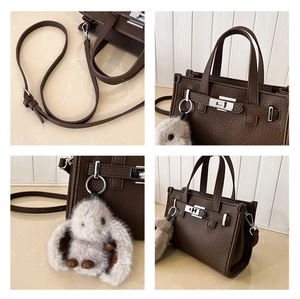 Detail view of dark brown pebbled leather handbag with silver lock and plush bunny charm