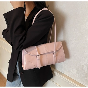 Close-up of pink rectangular baguette bag with decorative buckles on a shoulder