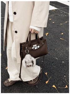 Detail of dark brown pebble leather handbag with silver lock and plush bunny charm