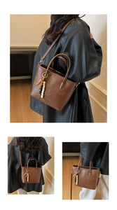 Close-up of vintage brown leather bag with fashion text and wooden beaded charm