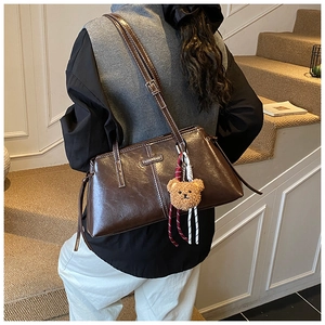 Deep brown glossy PU shoulder bag featuring twin thin straps and a plush bear pendant charm