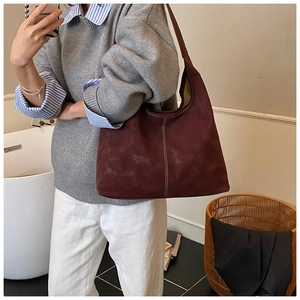 Detail of burgundy suede tote bag featuring distinctive white contrast stitching and soft texture