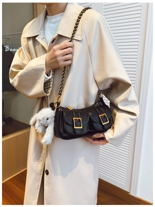 Detail of black leather bag with dual front pockets, gold buckles and plush bunny charm