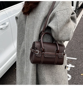 Detail of dark brown pebble leather handbag with white contrast stitching and metal buckle