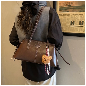 Deep brown retro glossy leather shoulder bag shown on model with a cute bear charm