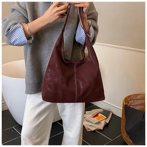 Macro detail of deep burgundy tote bag featuring premium matte finish and white contrast stitching
