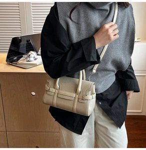 Beige pebble leather bag detail shown on a person with adjustable strap and top handles