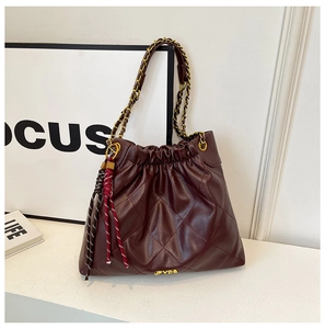 Detail of burgundy quilted bucket bag with gold chain strap and drawstring closure