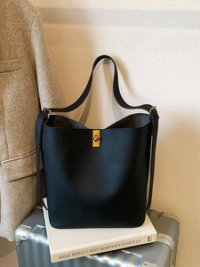 Sac seau minimaliste en cuir litchi noir avec fermoir rotatif doré pour un style urbain